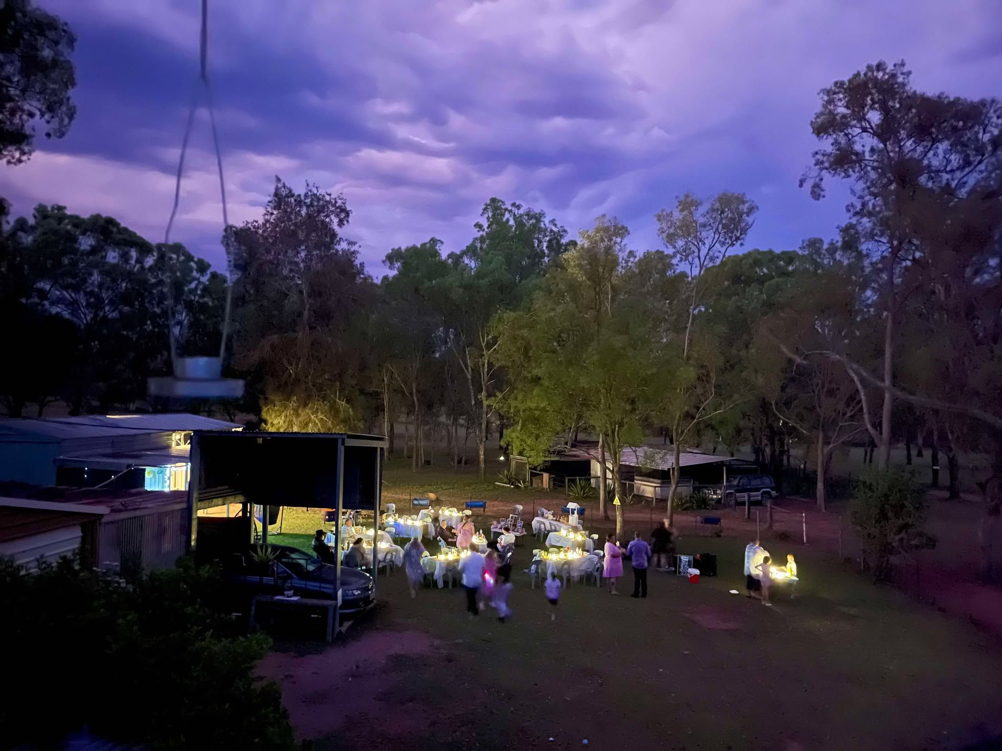 tables and chairs with people around them at venue in lockyer valley at twilight with purple clouds in sky