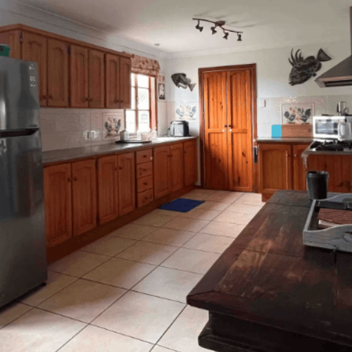 large kitchen with industrial stove, microwave on bench, timber doors