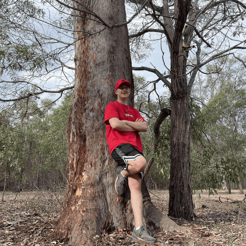 teen with red shirt leaning against large tree content creator space in churchable