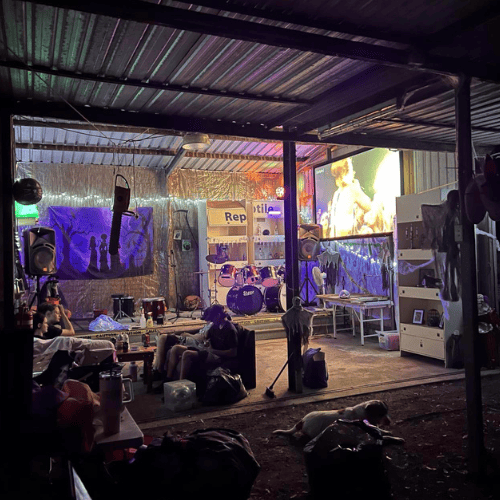 Venue with large screen, stage, instruments, lighting and people sitting talking to eachother at farm stay venue in lockyer valley