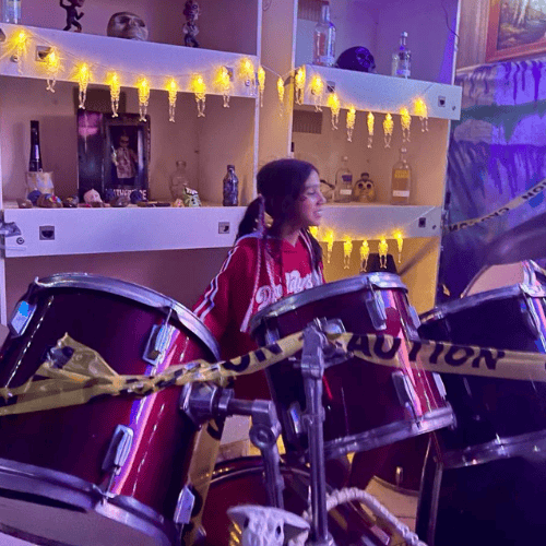 girl playing drums with lights behind her at venue in churchable