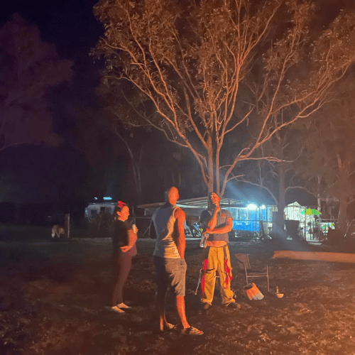 three people standing talking to eachother lit by firepit off camera at venue