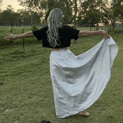 lady with silver dress standing with arms open wide in field in churchable