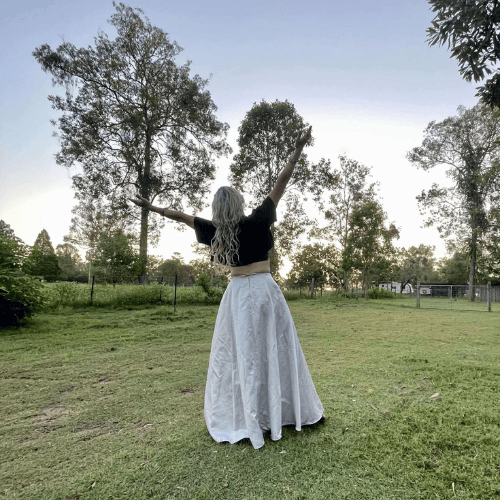 lady with silver skirt with arms up standing in field at photography venue near toowoomba