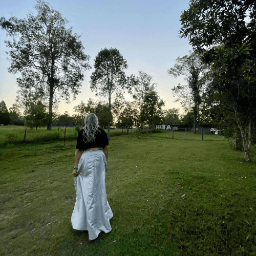 lady with silver skirt looking out over lush green field at photography venue near ipswich